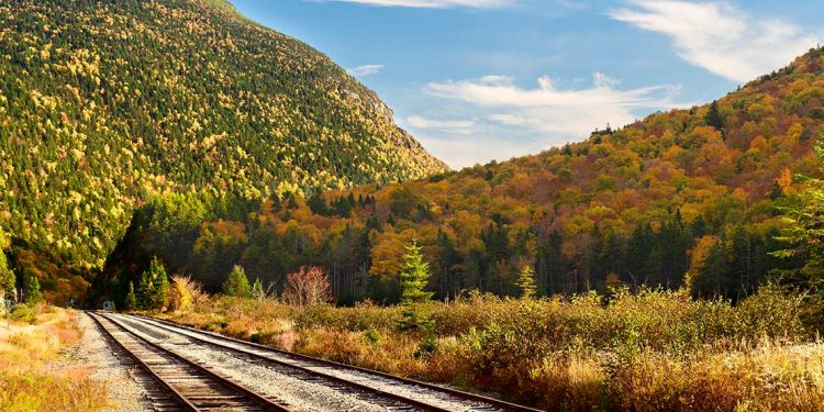 Railway track with mountain and woods in background, autumn colors