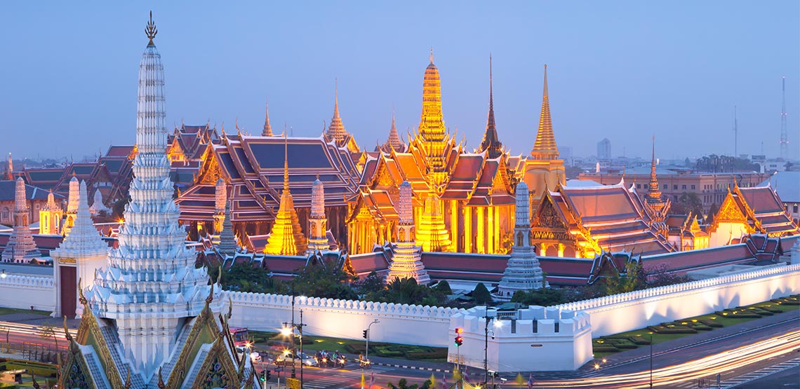 Palace glowing gold with white wall surrounding it.