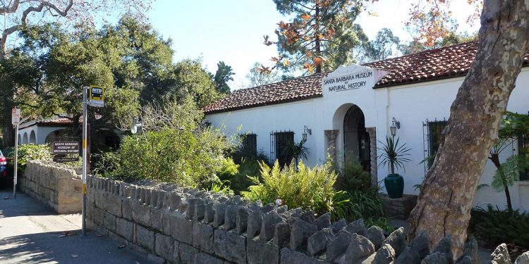 Small spanish style building with stone wall out front.