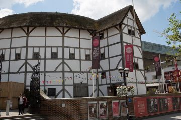 Globe Theatre, a white round building with brown thatched roof.
