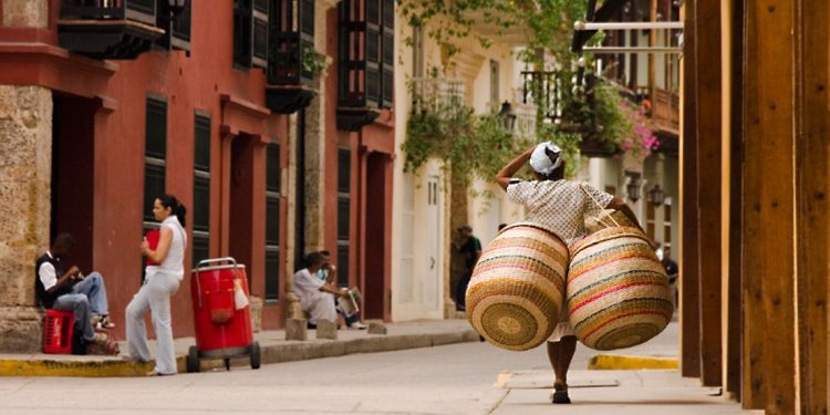 woman carrying baskets down a city street in Colombia