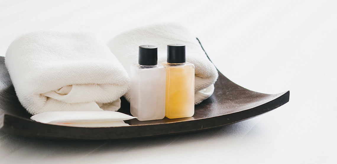 travel sized toiletries and towels on a decorative plate