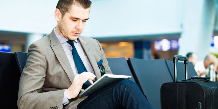 Man sitting at airport terminal on his tablet device