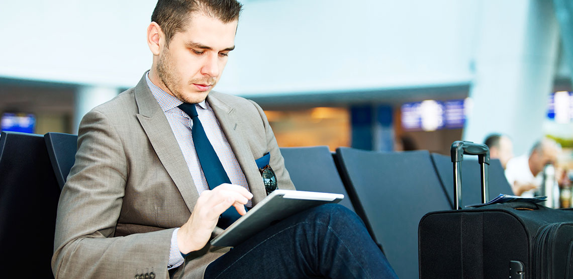 Man sitting at airport terminal on his tablet device