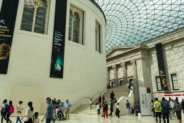 Inside museum with glass roof and white walls. People milling about.