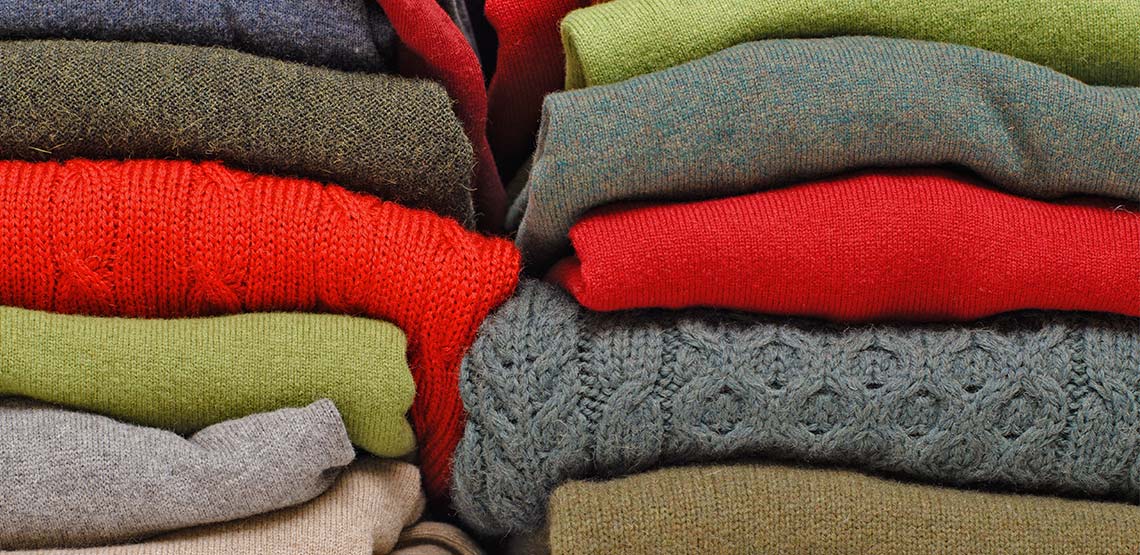 two stacks of knit sweaters in different colors