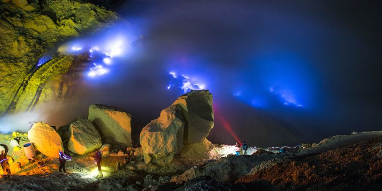 A dark cave in Kawah Ijen with people viewing the various rock formations