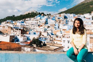 Woman sitting in blue ledge with Moroccan city in background