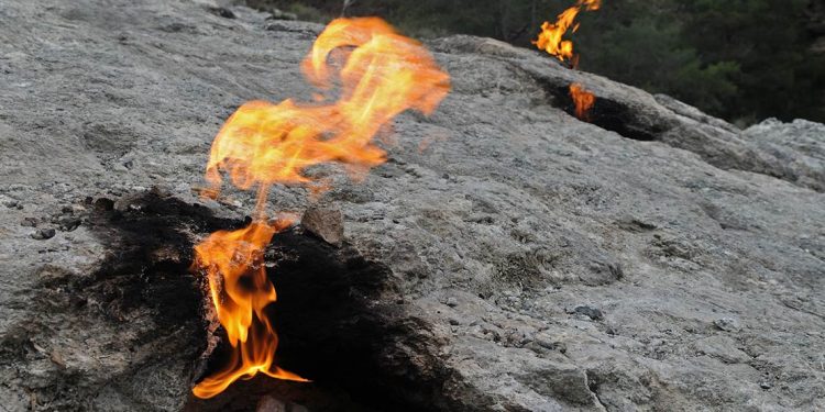 Volcanic rock and open flames on a cliff side in Olympos, Turkey