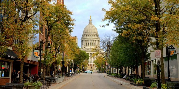 The Wisconsin State Capitol building at the end of a street lined with trees