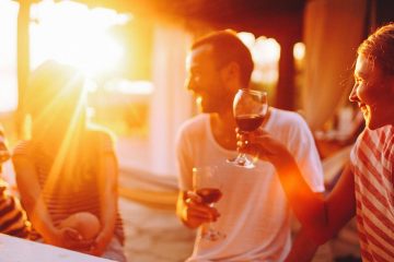 flare from sunset shines over friends laughing