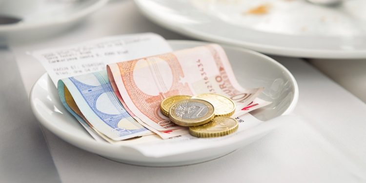 euro coins and bills folded in a white dish