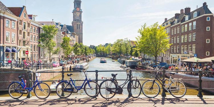 bikes line bridge overlooking channel in amsterdam, netherlands