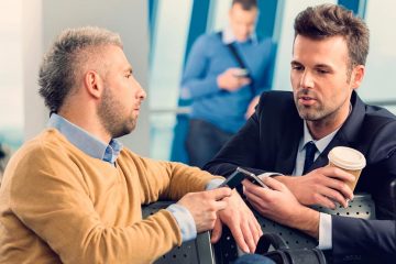 two men in business attire chatting in airport