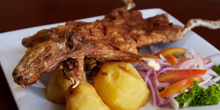 fried guinea pig over potatoes with side of vegetables