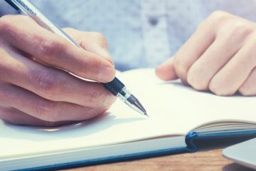 close up of hand writing in notebook