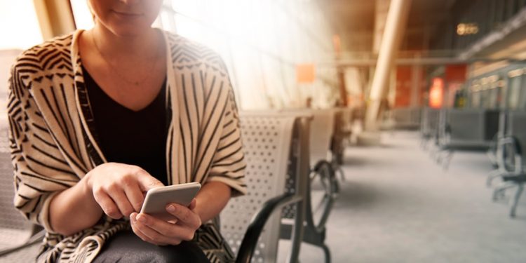 woman sitting in airport using smartphone