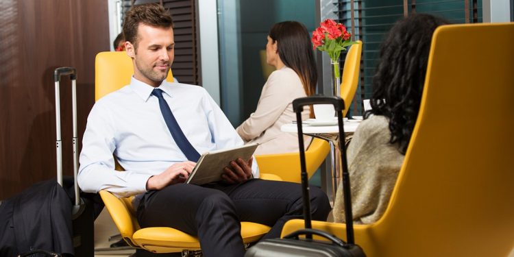 man in business attire sitting in comfy chair using ipad