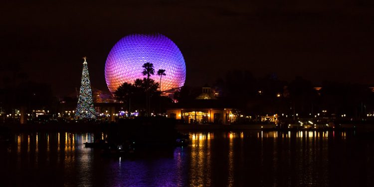A large Christmas tree and the Spaceship Earth sphere lit up against the night sky in Orlando