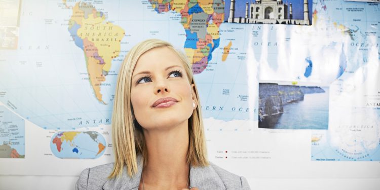 woman daydreaming in front of world map poster