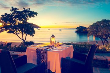 table for two overlooking ocean at sunset