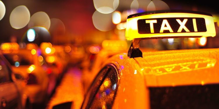 Row of taxis with their lights on at night