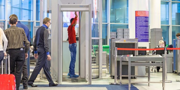 Man stands with his hands up in a scanning machine at the airport