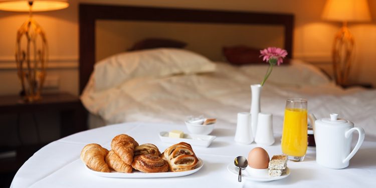 Breakfast foods including pastries and a boiled egg, sit on a table in a hotel room