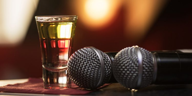 Two microphones sit next to a full shot glass
