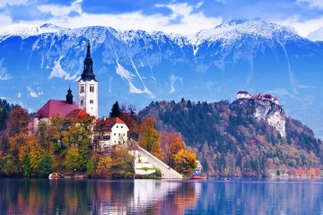 A church surrounded by fall trees with mountains in the background