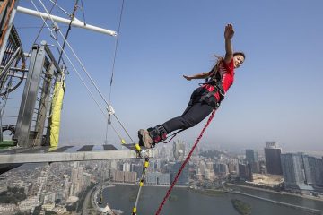 Woman stands with her arms out about to bungee jump off the Macau Tower