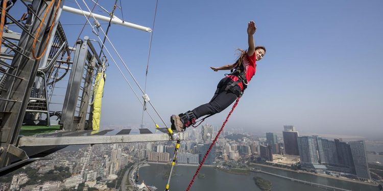 Woman stands with her arms out about to bungee jump off the Macau Tower