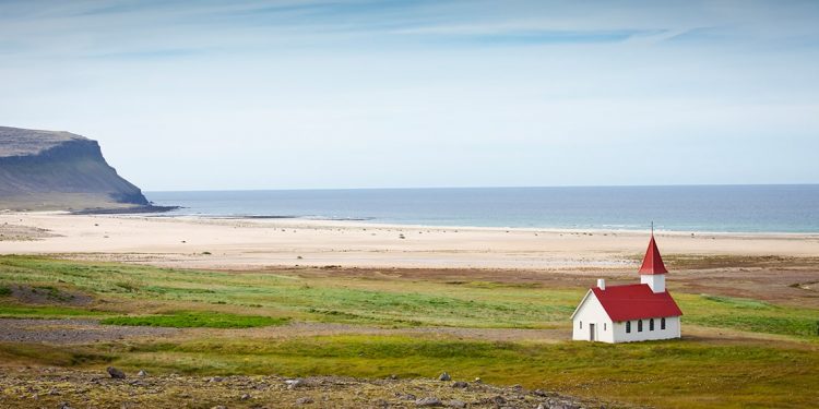 A lone church sits back from a beach in Iceland