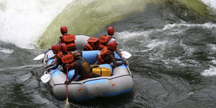 7 people in a rubber raft wearing helmets and life jackets about to go over large rapids