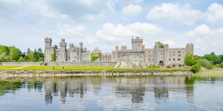 A well-kept Irish castle sits along a large moat of reflective water