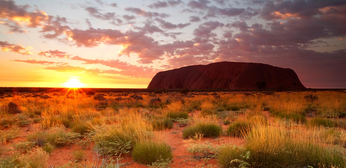 Uluru, or Ayers Rock, a sandstone monolith in Australia is on the right side of the sun setting