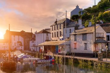 White stucco British houses are aligned around the city of Cornwall's boating dock as the sun sets