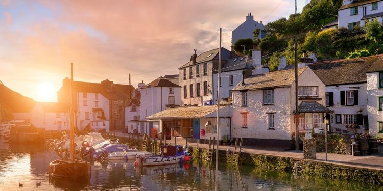 White stucco British houses are aligned around the city of Cornwall's boating dock as the sun sets