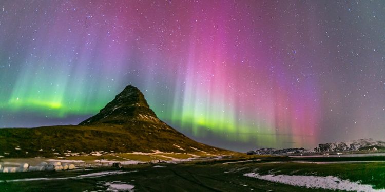 The colorful Northern lights dance behind one of many Iceland's mountains
