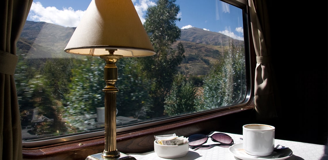 Window on a train with table, lamp, mug, sunglasses