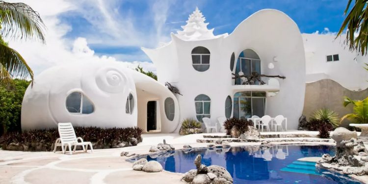 A white seashell inspired home comes is two stories high with an outdoor patio and swimming pool