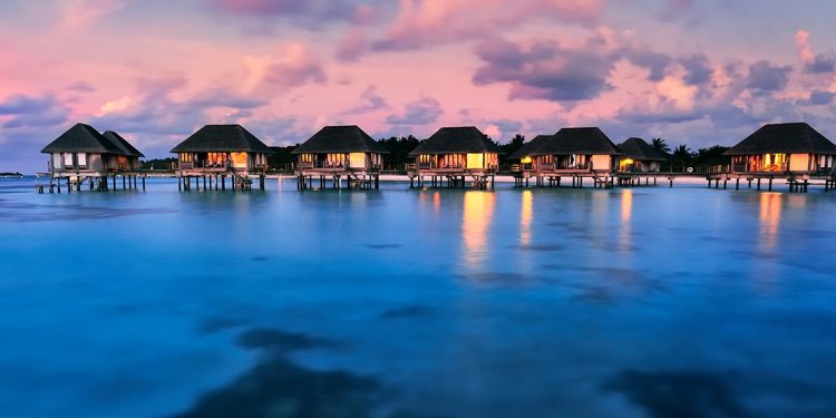 Six over-water villas with lights on