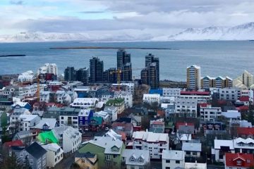 A panoramic view of the city of Reykjavik with the ocean and mountains in the background