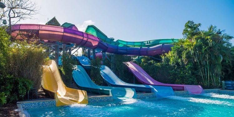 Four different colored water slides lead to a pool.
