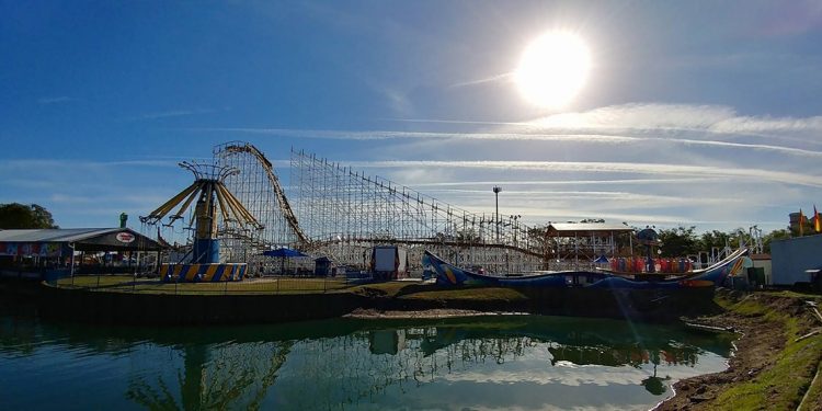 A theme park along a body of water featuring roller coasters and numerous thrill rides