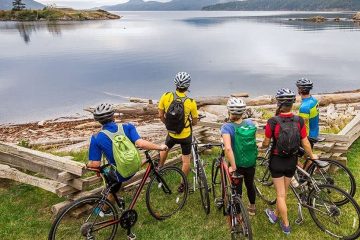 A family of bikers take a break to look straight at a body of water