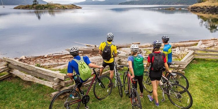 A family of bikers take a break to look straight at a body of water