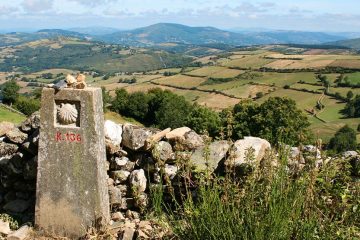 Stone pillar in front of stone wall looking out over patchwork fields.