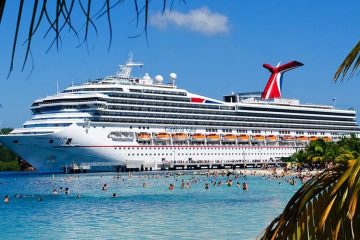 White cruise ship moored with people standing next to it in the water.