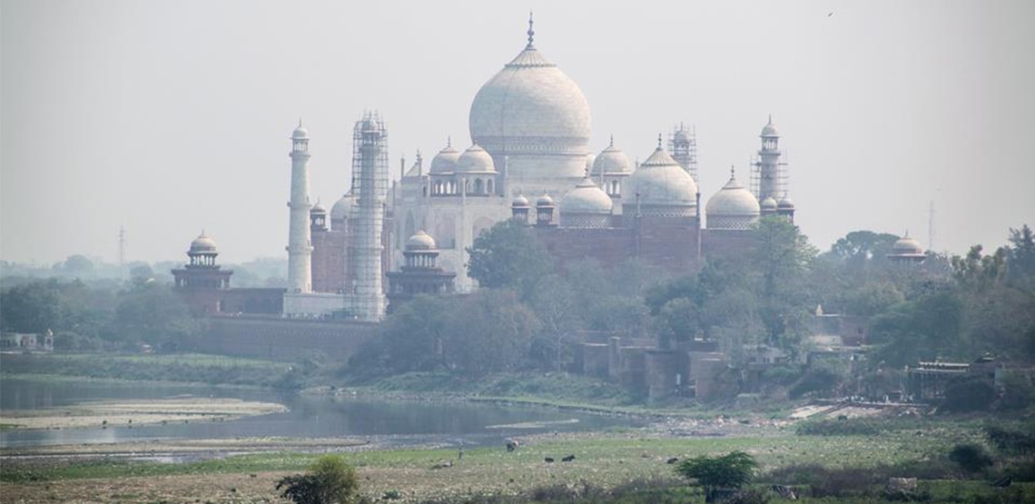 Back side of Taj Mahal with shallow water and stony ground.